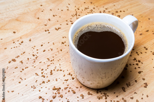 Cup of coffee and Coffee Granules on wooden table.