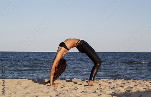 Young woman doing yoga at seaside
