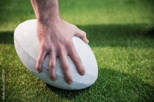 A rugby player posing a rugby ball