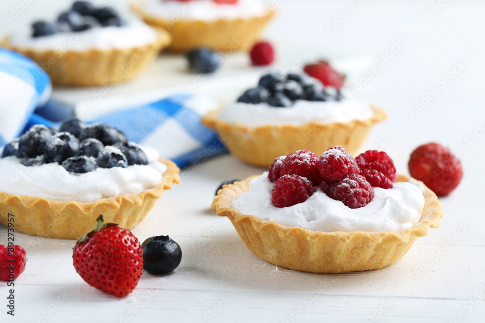 Dessert tartlets with berries on white wooden background Dessert tartlets with berries on white wooden background