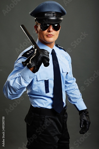 Fototapeta Portrait of policeman in sunglasses holding nightstick