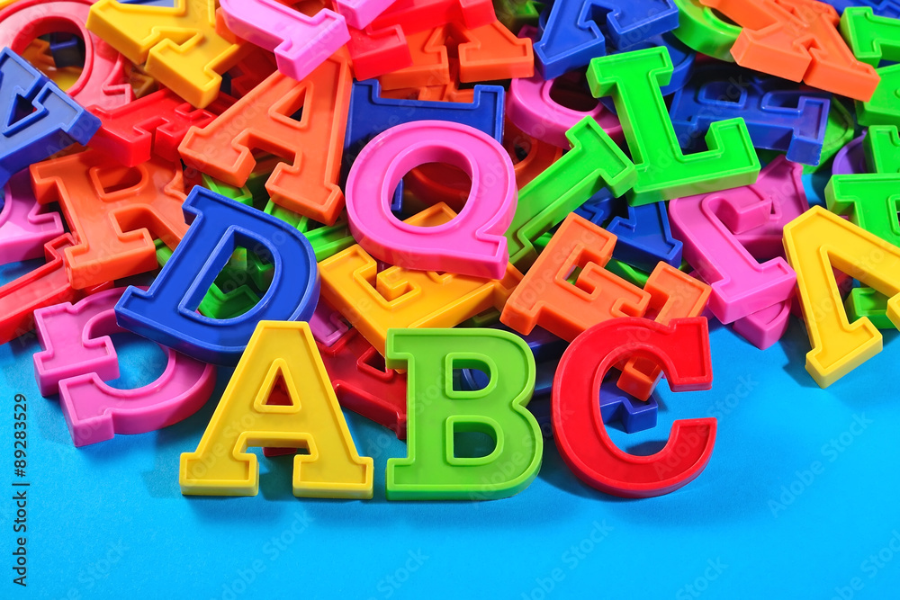 Fototapeta premium Plastic colored alphabet letters ABC on a blue