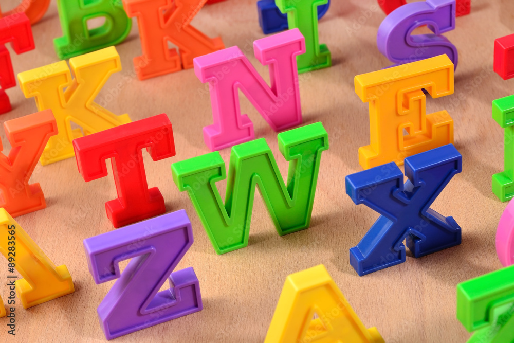 Plastic colorful letters close up on a wooden background Plastic colorful letters close up on a wooden background