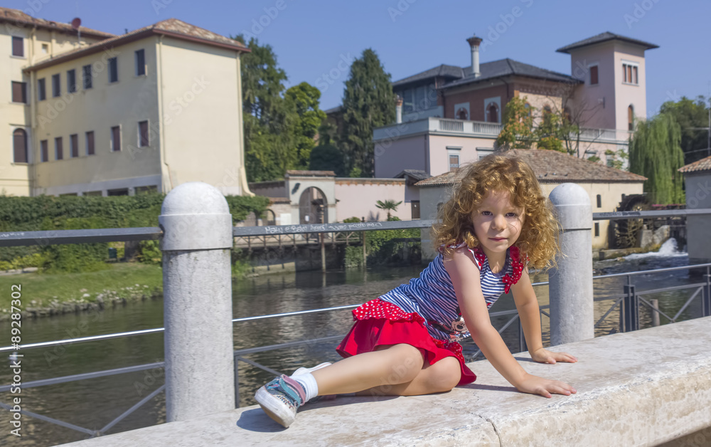 Bambina su panchina in marmo con sfondo di fiume