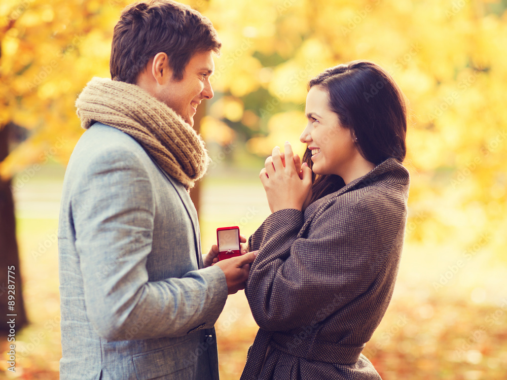 smiling couple with red gift box in autumn park smiling couple with red gift box in autumn park