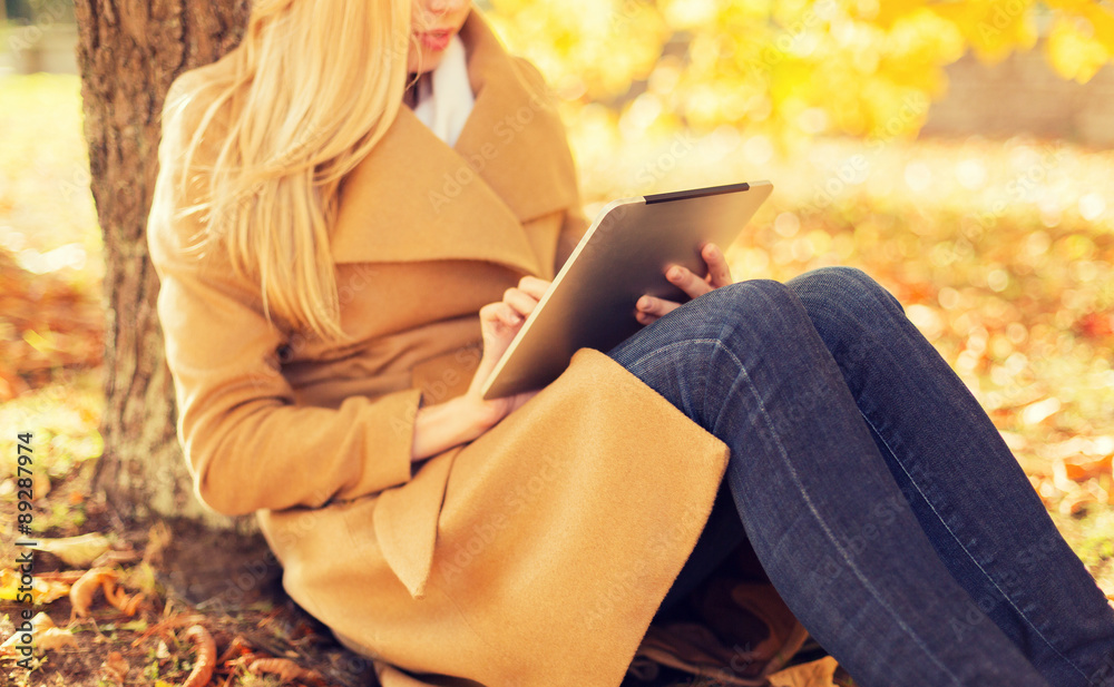 Obraz premium young woman with tablet pc in autumn park