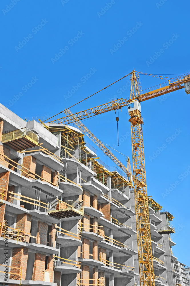 Crane and building construction site against blue sky