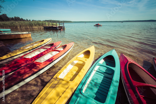 Fototapeta Naklejka Na Ścianę i Meble -  Colorful kayaks moored on lakeshore, Goldopiwo Lake, Mazury, Pol