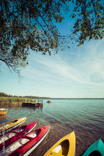 Fototapeta Naklejka Na Ścianę i Meble -  Colorful kayaks moored on lakeshore, Goldopiwo Lake, Mazury, Pol