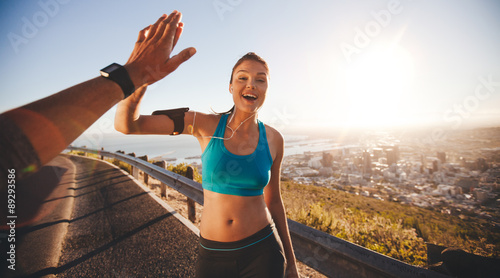 Fit young woman high fiving her boyfriend after a run photo