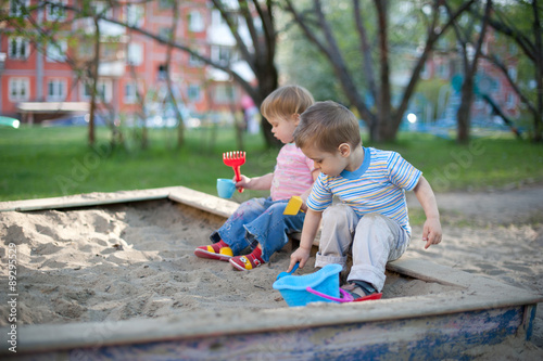 Two cute little children brother and sister playing in a sandbox