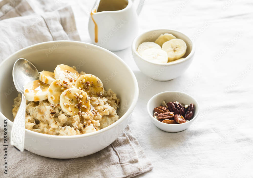 oatmeal with banana, caramel sauce and pecans in a white bowl on a light surface, a delicious and healthy Breakfast oatmeal with banana, caramel sauce and pecans in a white bowl on a light surface, a delicious and healthy Breakfast