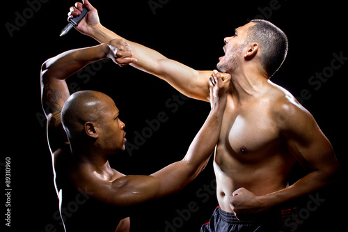 Martial arts instructor demonstrating self defense against a knife attack photo