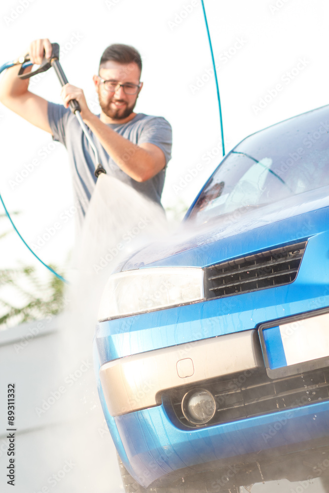 Fototapeta premium Man washing his car with using a high pressure water jet