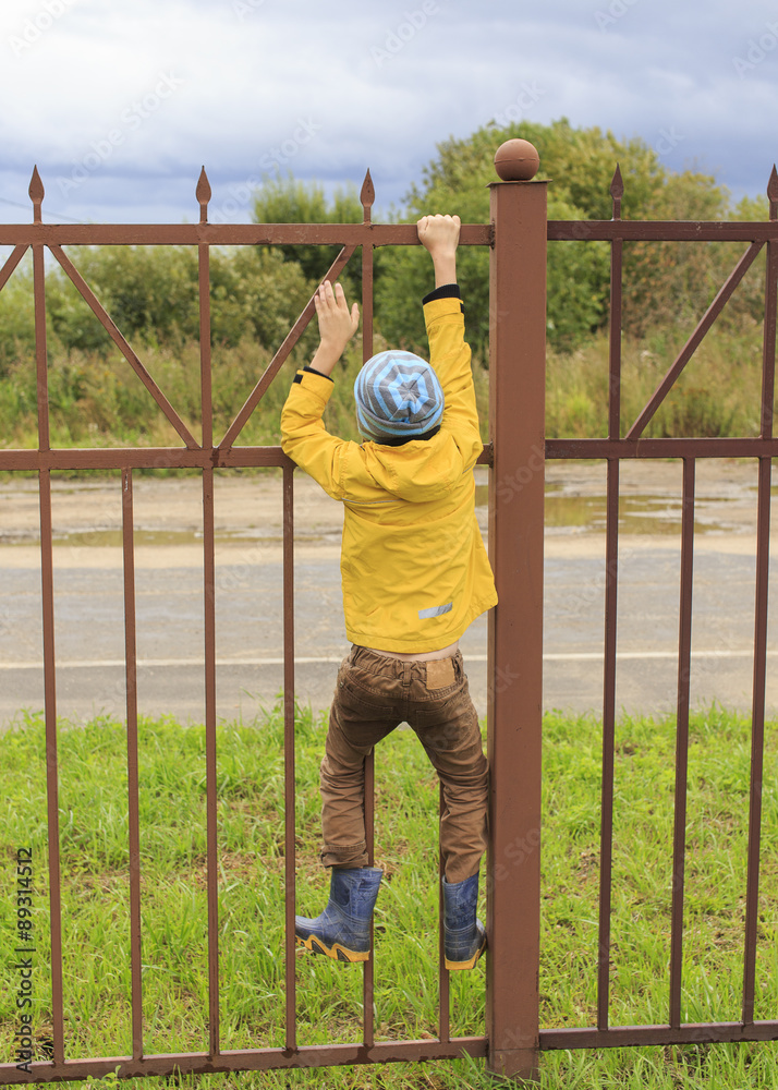 Obraz premium Boy on a fence. the boy climbed onto a high fence