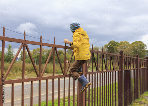 climb fence. Boy going to climb over the high fence