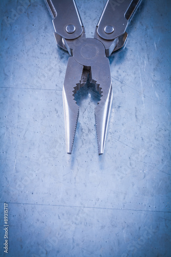 Metal nippers on scratched metallic surface construction concept photo