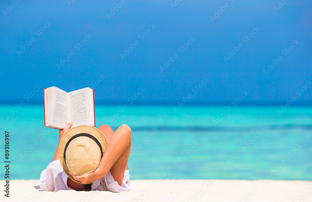 Young woman reading book during tropical white beach