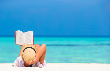 Young woman reading book during tropical white beach