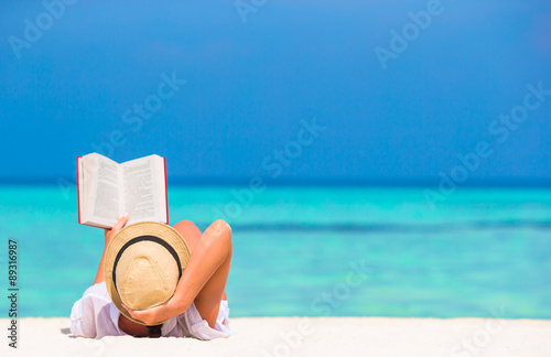 Obraz na płótnie Young woman reading book during tropical white beach w salonie