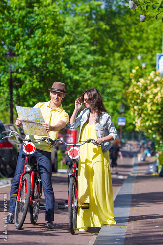 Photography Young tourists couple looking at map with bikes in european city