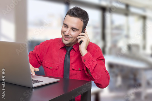 Man working in office, talking on his cell phone 