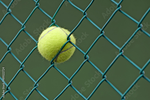tennis ball in the chainlink behind court