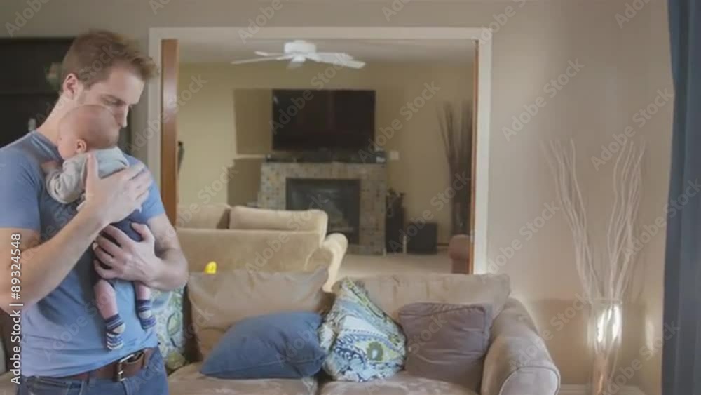 Father walking and bouncing newborn son in living room Father walking and bouncing newborn son in living room