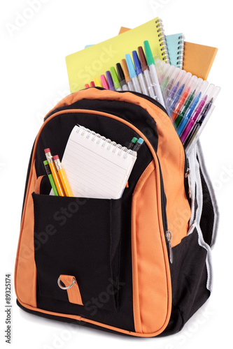 School satchel bag backpack with various books pencils crayons and study equipment isolated on white background photo