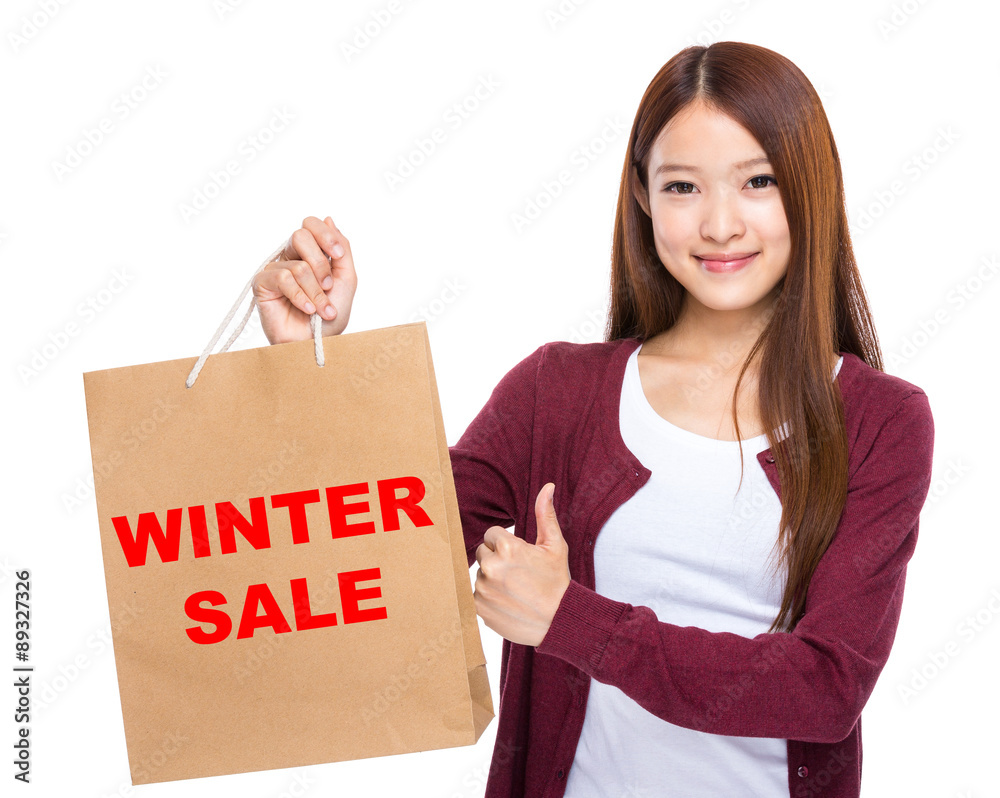 Woman with shopping bag and thumb up for showing winter sale Woman with shopping bag and thumb up for showing winter sale
