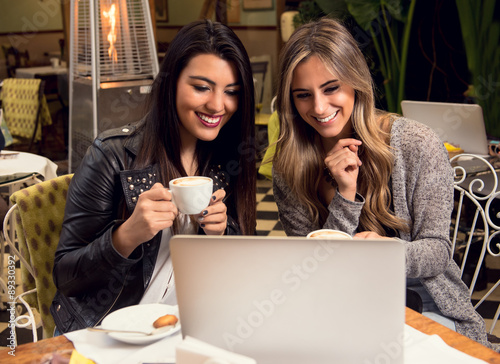 Two girlfriends sharing information while having a coffee