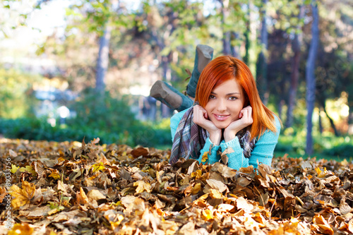 Young woman laying in the leaves in park  looking at camera