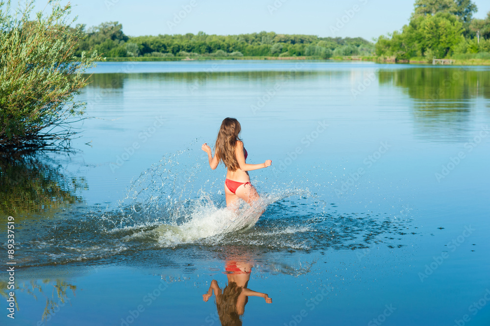 Fototapeta premium Girl in red bikini run into water