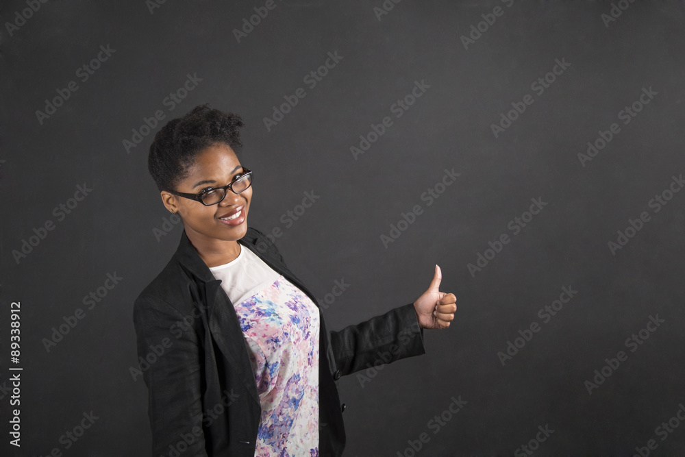 African woman with thumbs up hand signal on blackboard background African woman with thumbs up hand signal on blackboard background