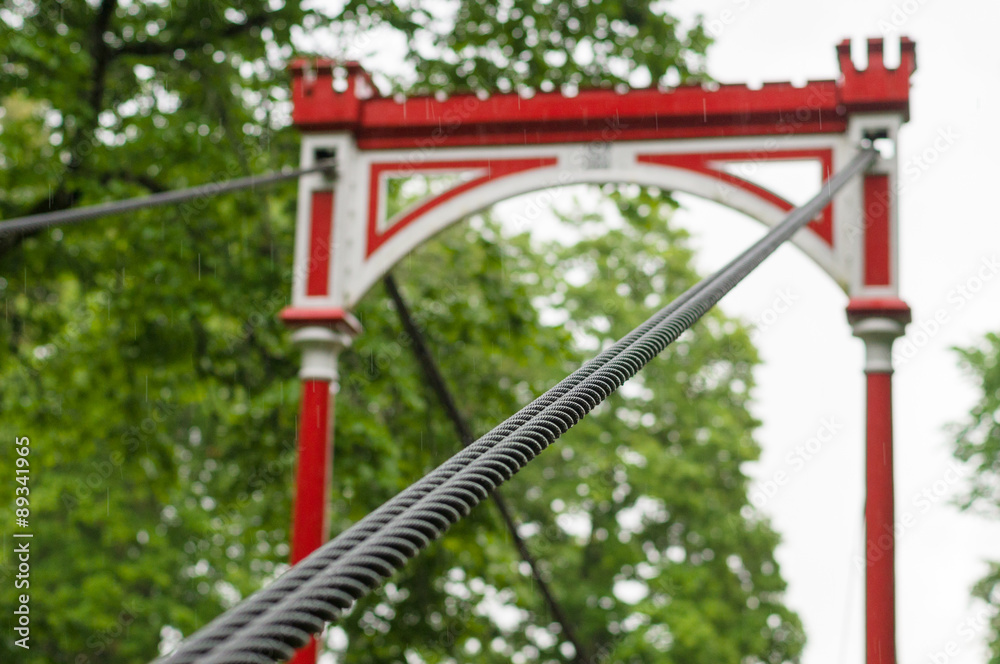 Retro style bridge in the rain, selective focus on steel ropes bundle Retro style bridge in the rain, selective focus on steel ropes bundle