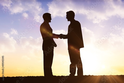 Composite image of silhouettes shaking hands