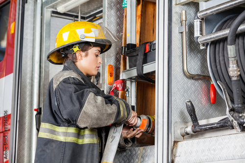 Female Firefighter Fixing Water Hose In Truck