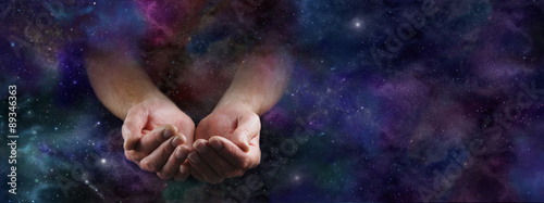Our Abundant Universe - Male hands emerging from a wide dark deep space background gesturing with cupped hands photo