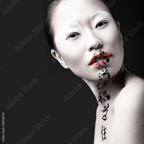 Beautiful Asian girl with white skin, red lips and hieroglyphics
