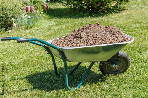 Wheelbarrow with dirt  in the  garden. Household plot. Dacha