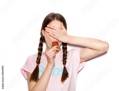 Portrait of cute girl holding ripe strawberry