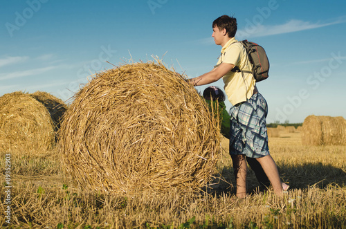 Children roll haystack on the field