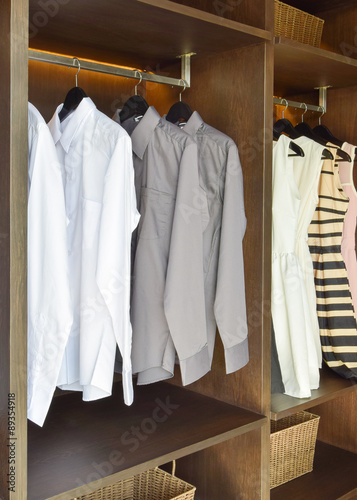 row of white and gray shirts hanging in wooden wardrobe