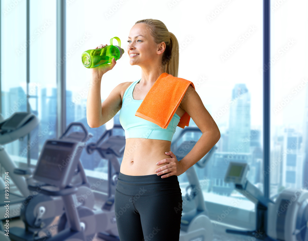 happy woman drinking water from bottle in gym happy woman drinking water from bottle in gym