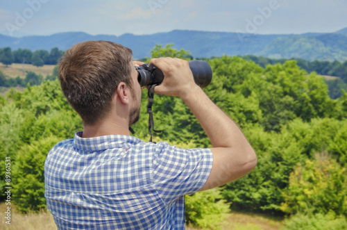 Young man looking through a binocular