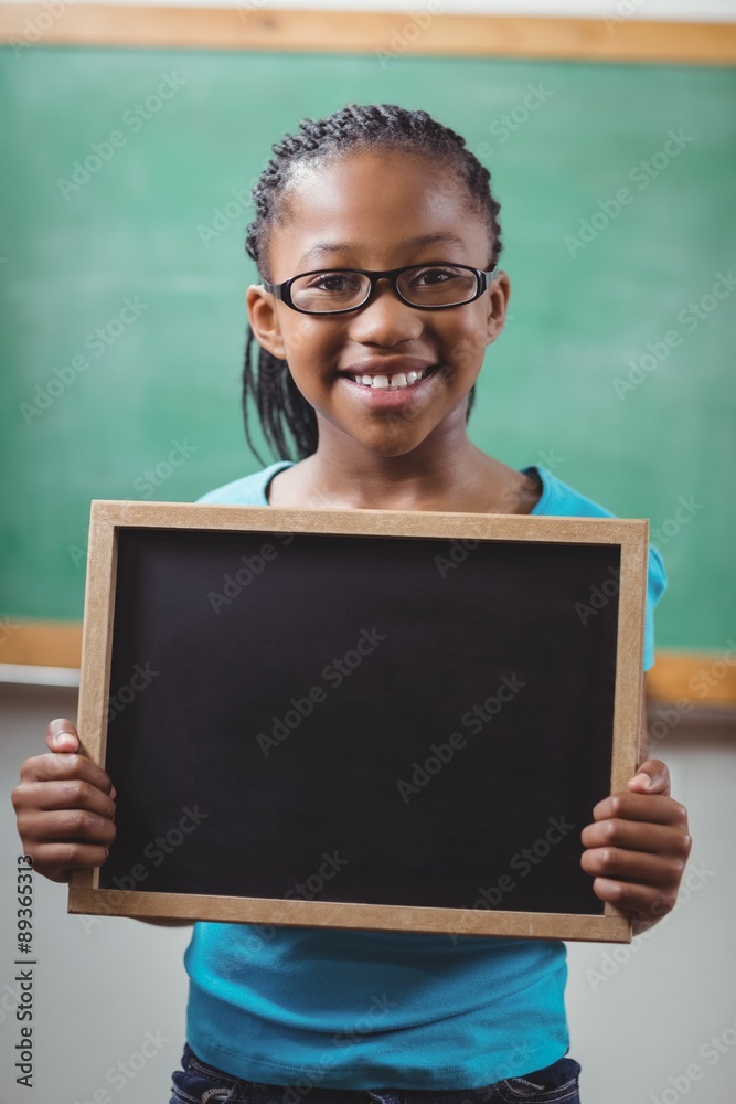 Smiling pupil holding chalkboard in a classroom Smiling pupil holding chalkboard in a classroom