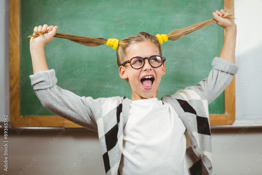 Cute pupil pulling her hair in a classroom