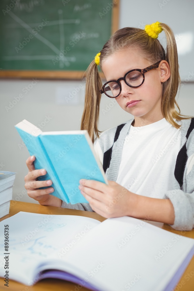 Concentrated pupil reading book at her desk Concentrated pupil reading book at her desk