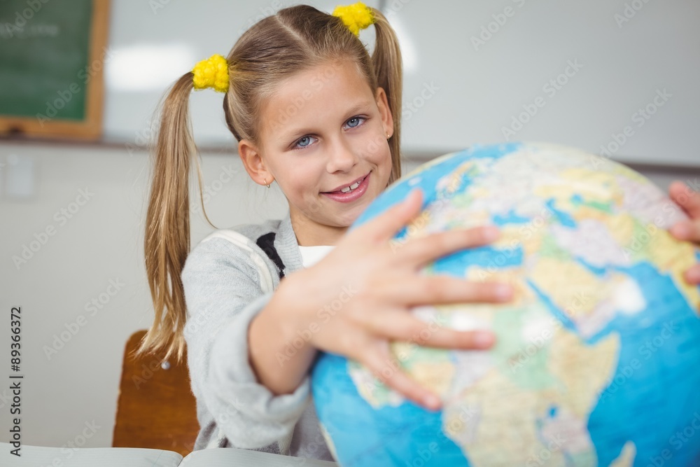Cute pupil holding globe in a classroom Cute pupil holding globe in a classroom