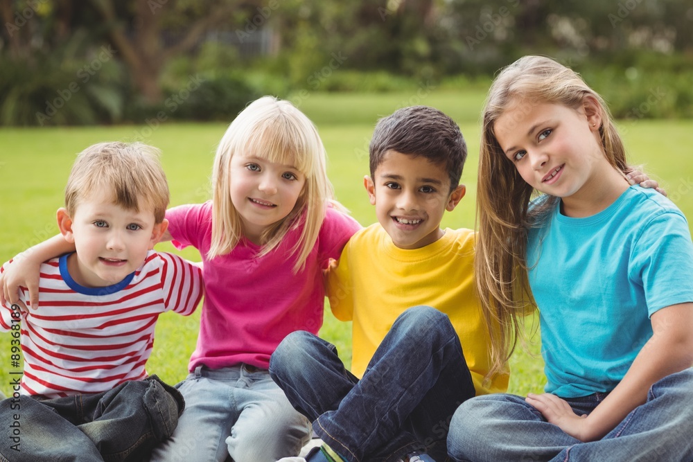 Fototapeta premium Smiling classmates sitting in grass 